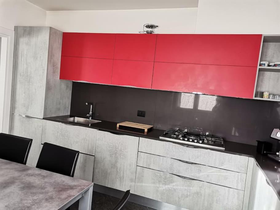 La cuisine est équipée de placards rouges, d'un évier et d'une table. dans l'établissement Da Laura, à Grosio