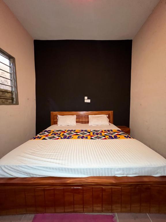 a bedroom with a large bed with a black wall at DG Hôtel in Cotonou