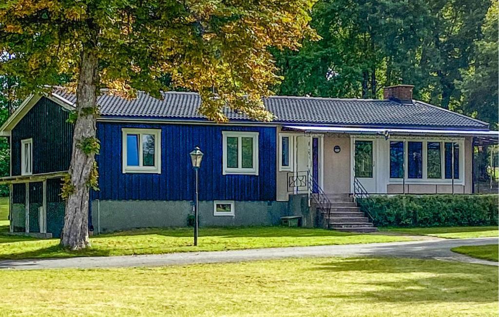 a blue house with a tree in front of it at Lovely Home In Ormaryd With Sauna in Ormaryd