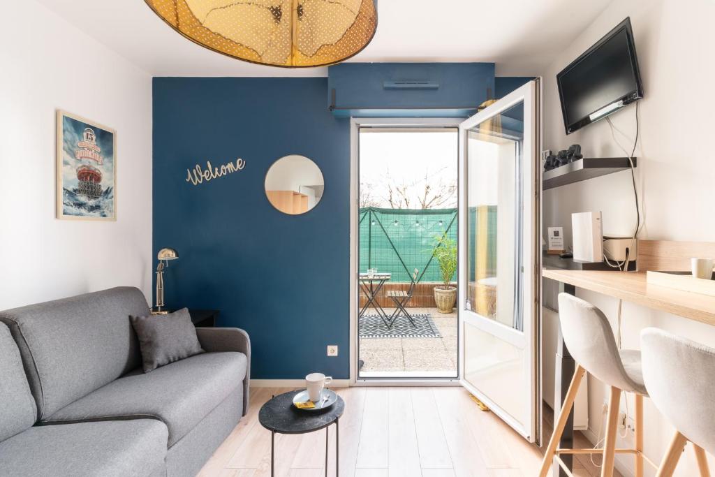- un salon avec un canapé gris et un mur bleu dans l'établissement Studio Centre-Ville avec Terrasse et Parking Sécurisé Gratuit, à Nantes