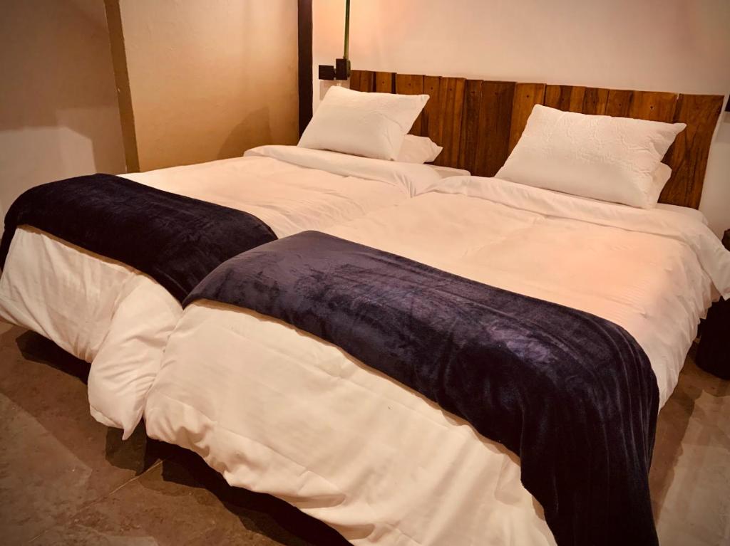 Hotel Quinta Bolivar في بوغوتا: سريرين في غرفة ذات أغطية ووسائد بيضاء