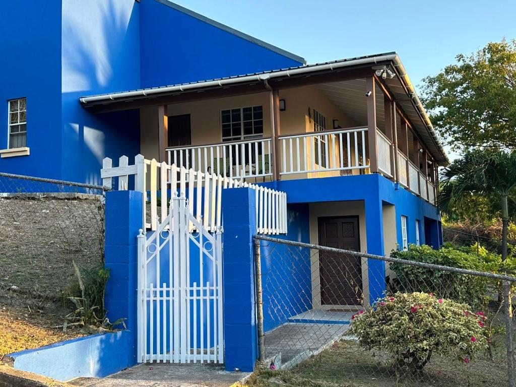 a blue house with a white gate at Sea-Renity Hideaway (Studio Apt) in Woods