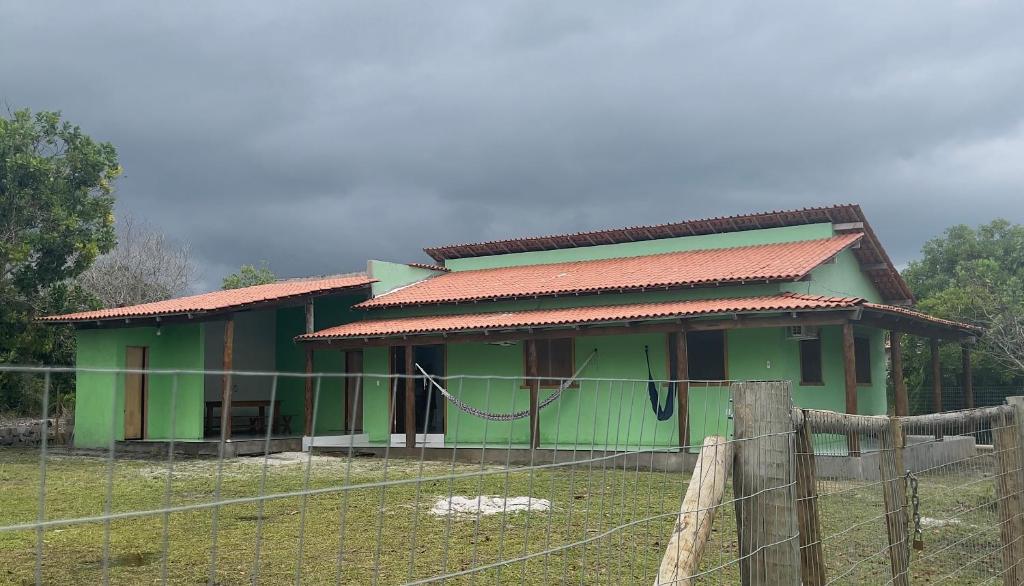 une maison verte avec une clôture devant elle dans l'établissement Green House, à Corumbau