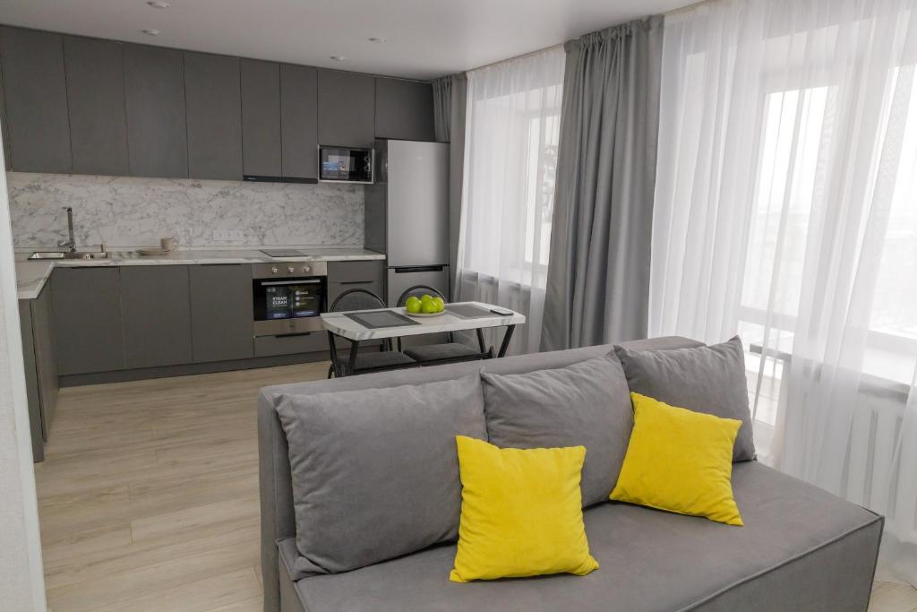 uma sala de estar com um sofá cinzento com almofadas amarelas em Сomfortable apartment in the central square em Öskemen