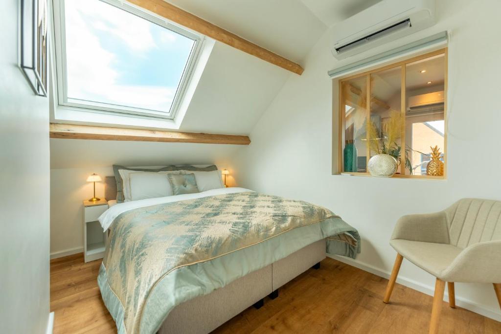 1 dormitorio con cama, ventana y silla en La Loge Bed & Breakfast, 