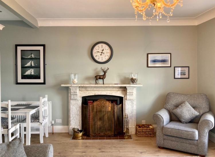 a living room with a fireplace with a clock on the wall at Tonn Ruray Sea View Luxury 2 Bed Apartment in Dundrum