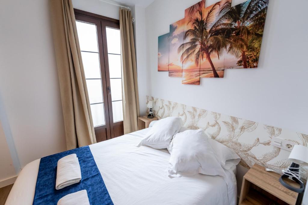 a bedroom with a bed with a palm tree picture on the wall at Apartamentos Jardines de la Sitarilla in Granada