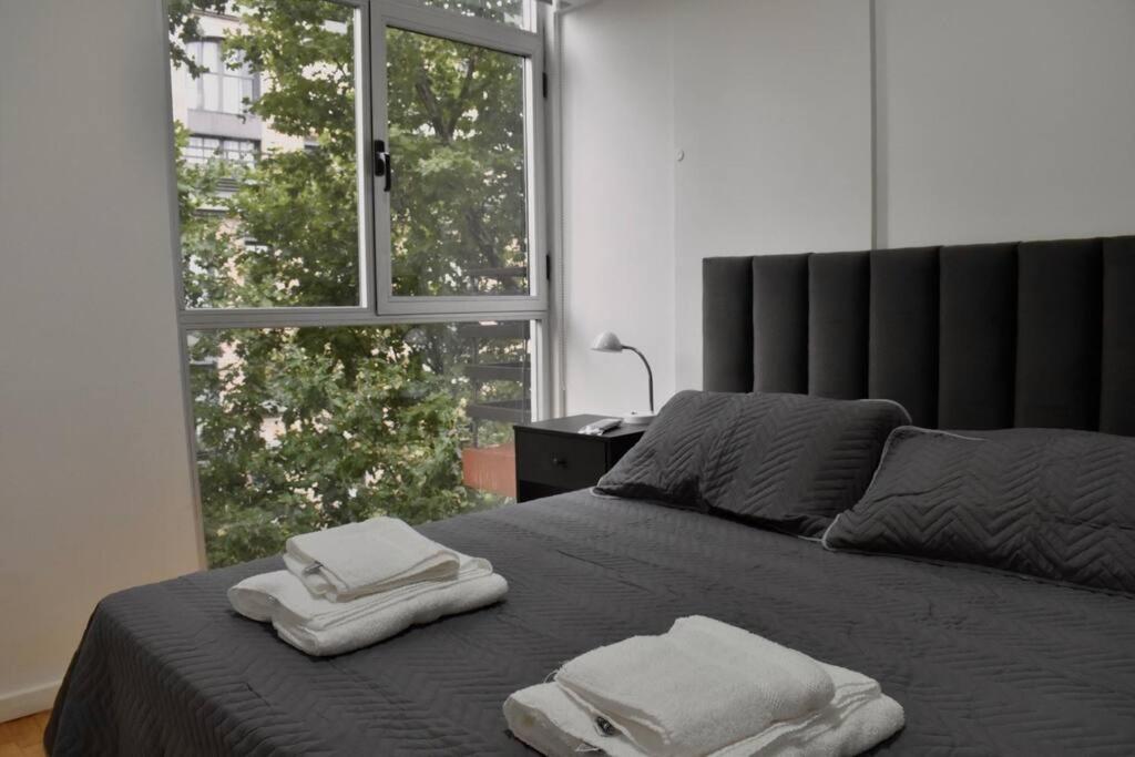 1 dormitorio con 2 toallas en una cama con ventana en Amplio piso La Rural Embajada USA Shopping Outlet en Buenos Aires