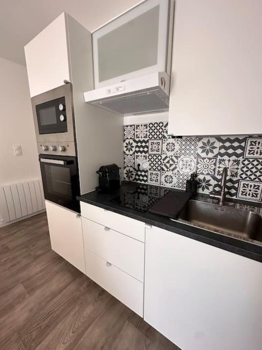 une cuisine avec des armoires blanches et un comptoir noir dans l'établissement Super maison f2… avec jardin, à Bondy