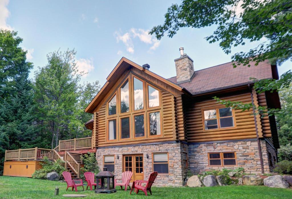 a log home with rocking chairs in the yard at Chalet Authentik 27 - Hot tub, Pools, Lake & Resort in Mille-Isles