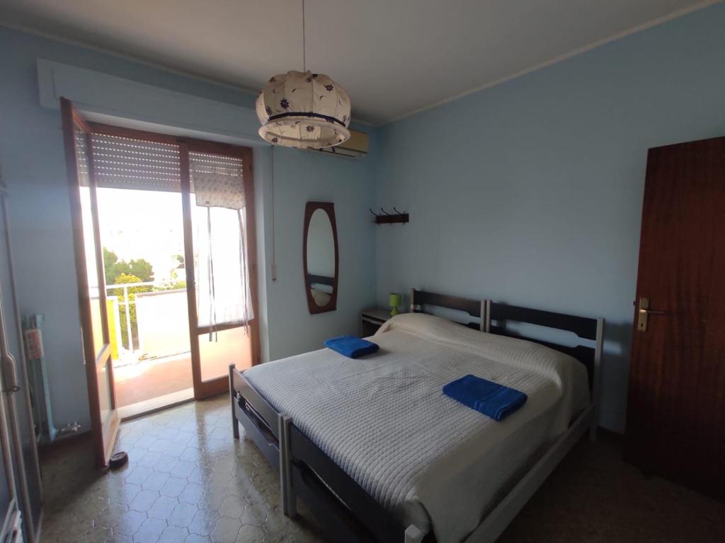 een slaapkamer met een bed met blauwe lakens en een raam bij La Riva in Porto Recanati