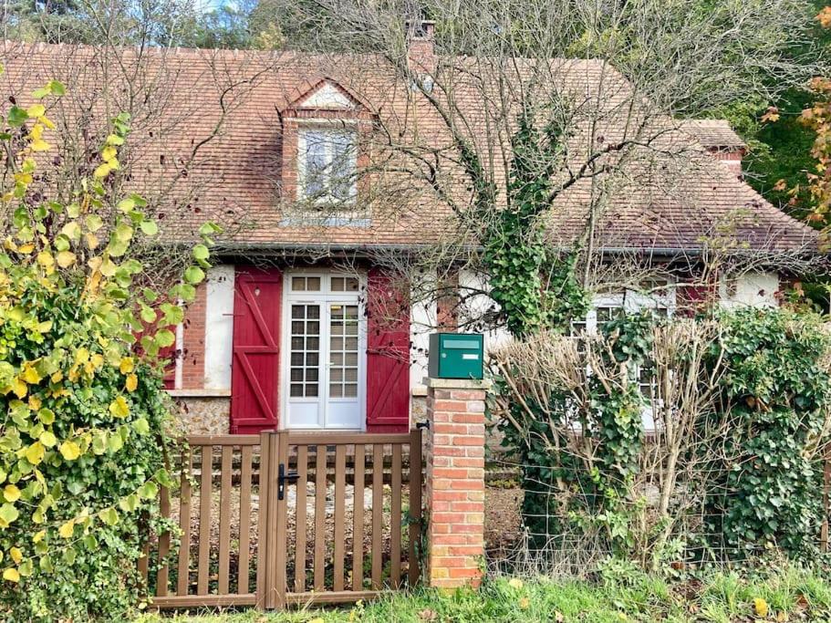 une vieille maison avec une porte rouge et une clôture dans l'établissement Cottage normand, à La Croisille
