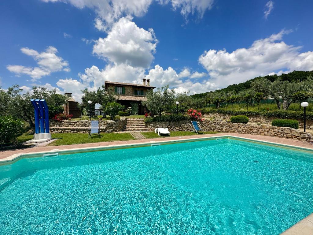 a blue swimming pool in front of a house at Villa Tilla in Gualdo Cattaneo
