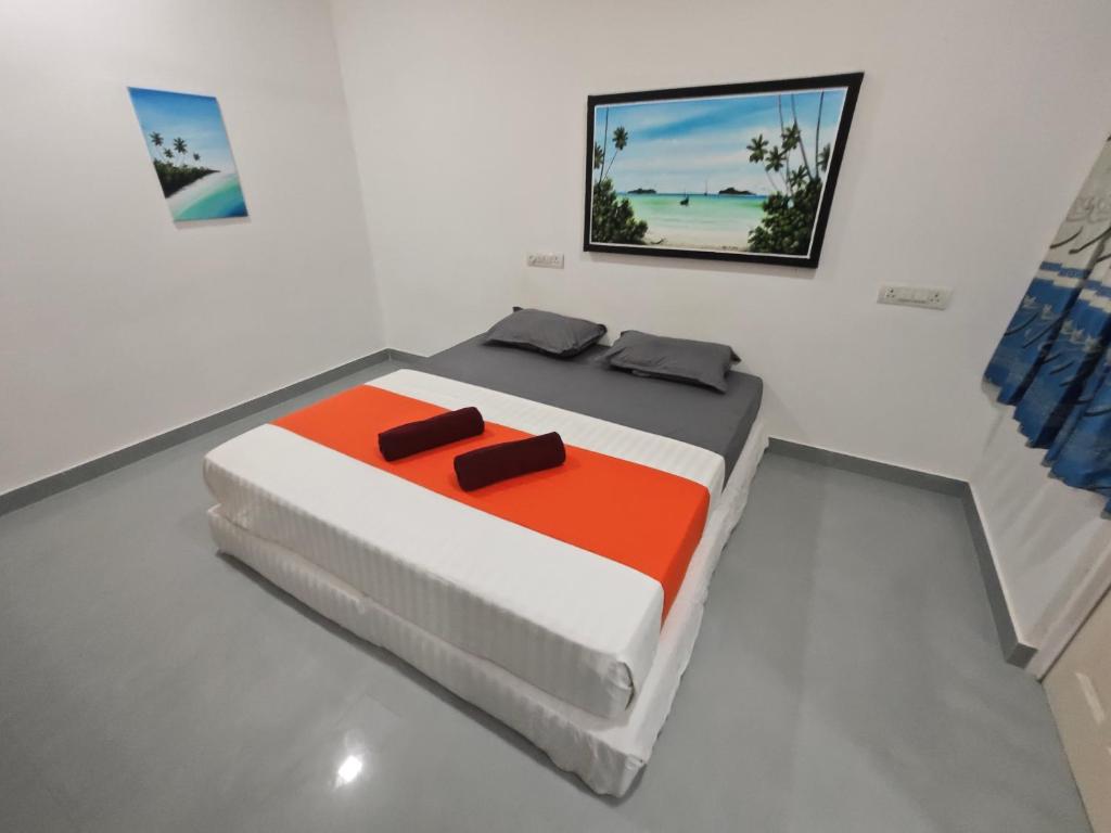 Habitación blanca con cama con edredón naranja y blanco en Miyaru Lodge Divers en Mandhoo