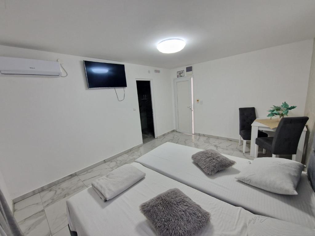 a white room with two beds and a tv on the wall at Carigradski Drum Plus in Radinac