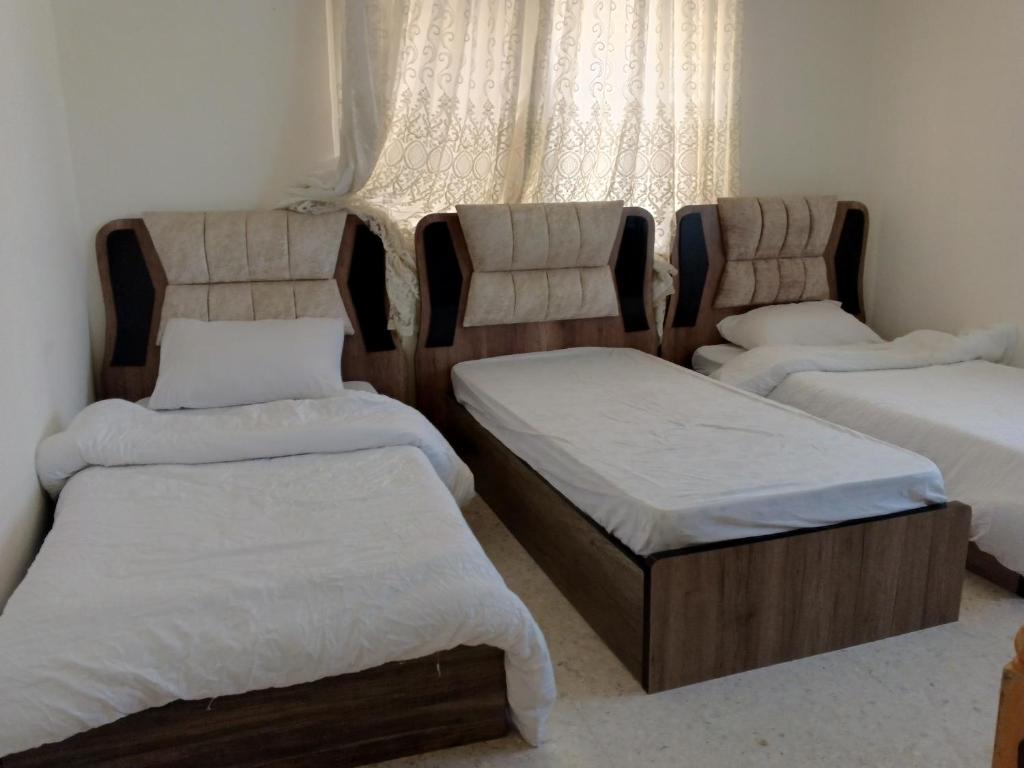 Habitación con 3 camas y ventana en Sebstian Rooms en Madaba