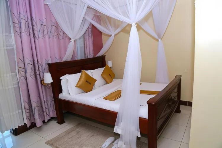 ein Schlafzimmer mit einem Himmelbett in der Unterkunft Jade Spa and Hotel in Kasese