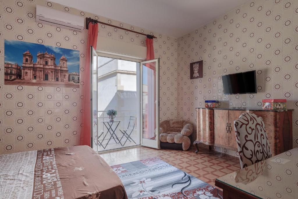 sypialnia z łóżkiem i przesuwanymi szklanymi drzwiami w obiekcie Casa Caterina w mieście Noto