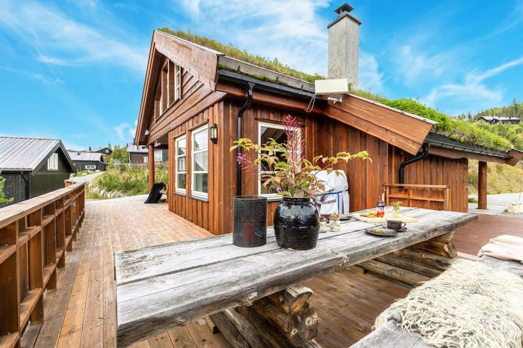 una pequeña casa de madera con terraza de madera en Cozy cabin with sauna, ski tracks and golf outside, en Gol
