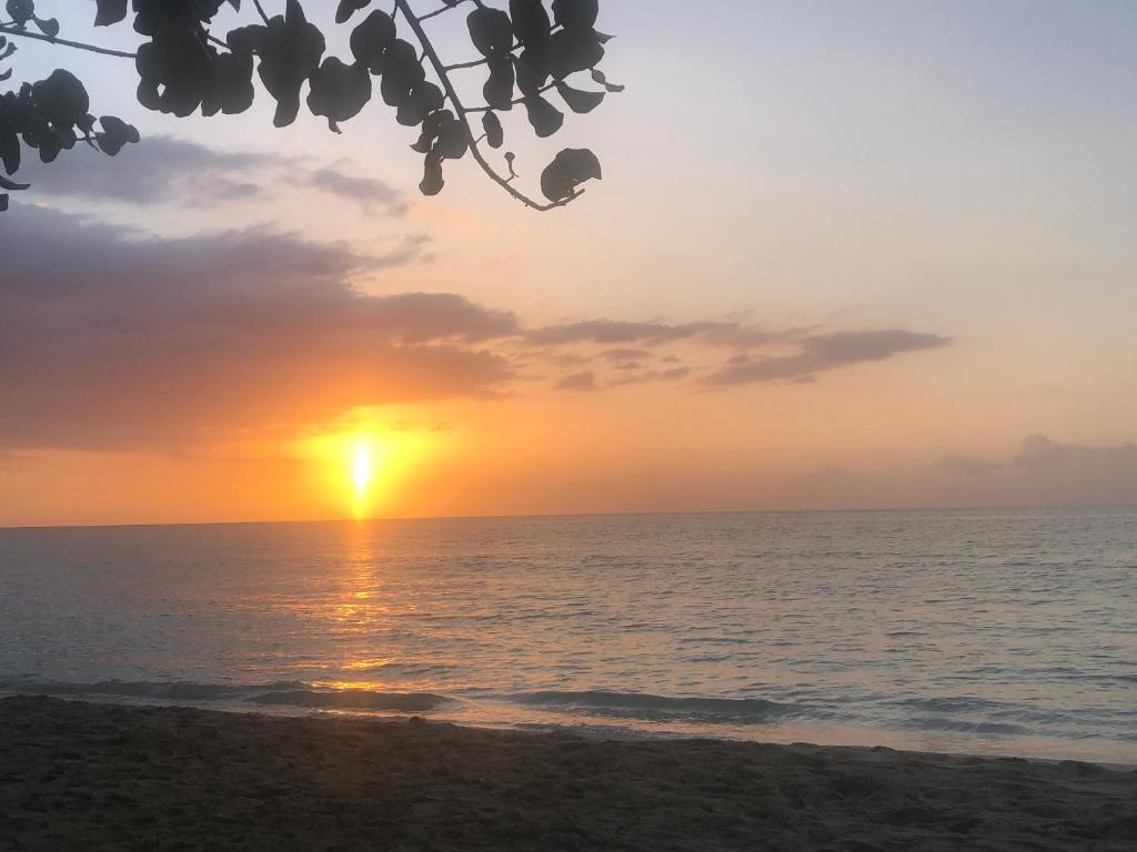 a sunset on the beach with the ocean at Andre's Guest House in Negril