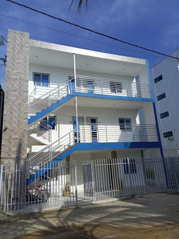 een wit appartementencomplex met blauwe balkons en een hek bij Apartamentos Mi Reserva OK - Miraluna in Coveñas