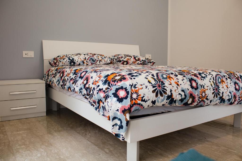 a white bed with a floral comforter and pillows at Casa di Nonna Rosy in Naples