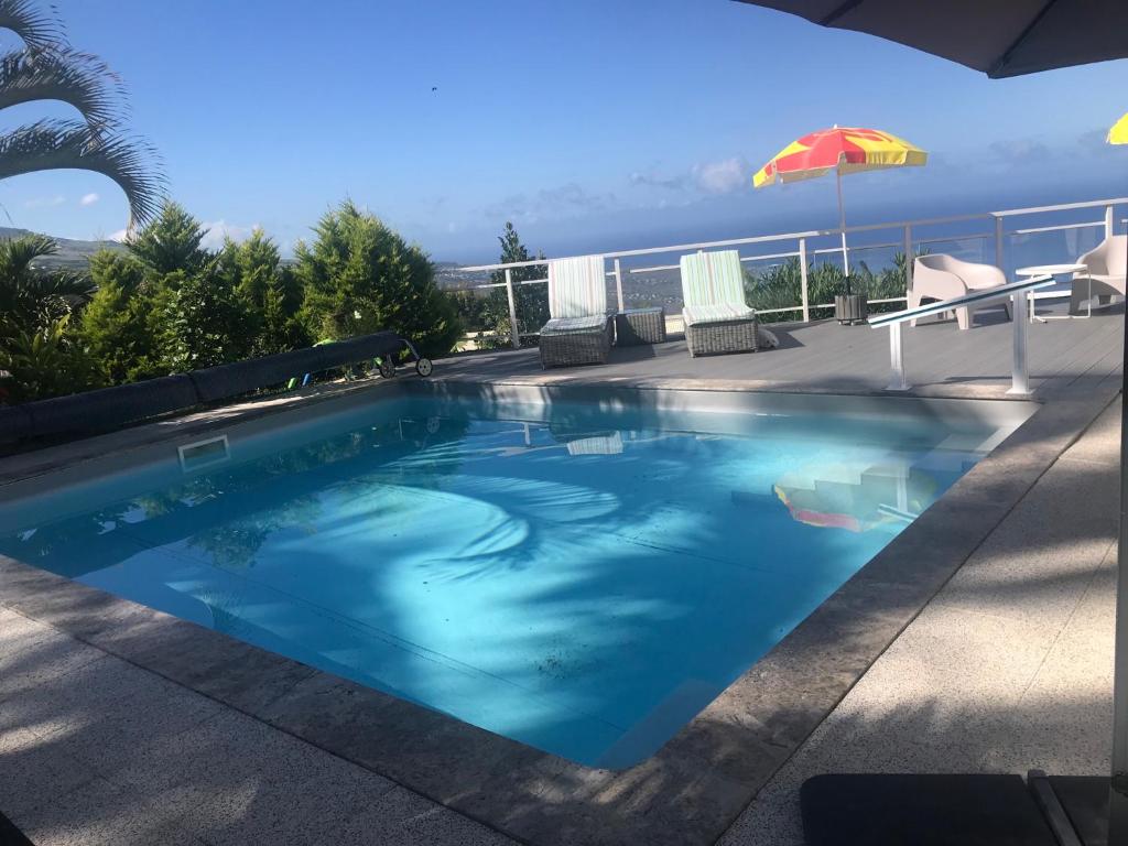 - une piscine sur une terrasse avec un parasol dans l'établissement Entre ciel et mer piscine chauffée, à Saint-Leu