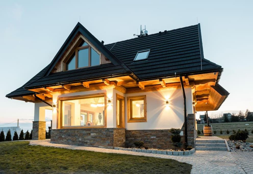 een klein huis met een zwart dak bij Czorsztyn Ski&Sail Aparthouse in Maniowy