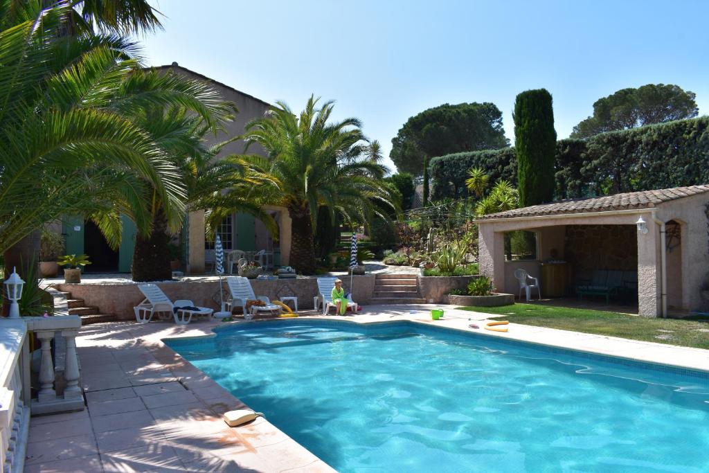 une piscine avec des palmiers dans une arrière-cour dans l'établissement Appartement Rez de Villa - 4 personnes - Fréjus - Vue piscine, à Fréjus