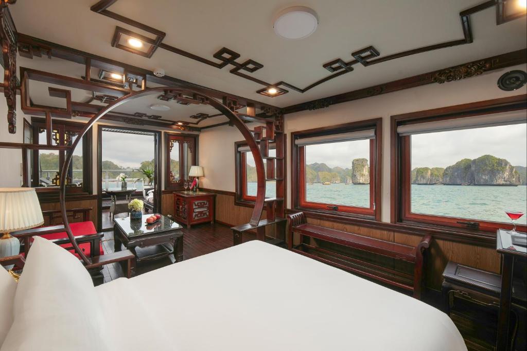 Zimmer mit einem Bett und Fenstern auf einem Boot in der Unterkunft Majestic Legend Cruise in Hạ Long