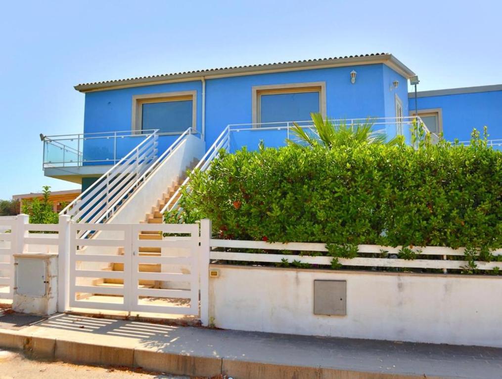 een blauw huis met een wit hek ervoor bij La terrazza della Dolce Casa - Blue Wave - Casuzze in Villaggio Azzurro