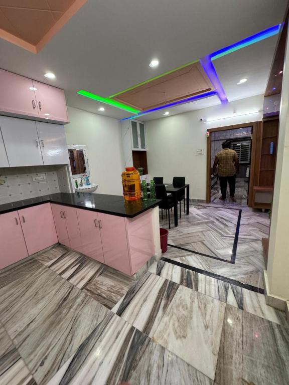 an empty kitchen with pink cabinets and a table at Karthikeya villa’s in Narasaraopet
