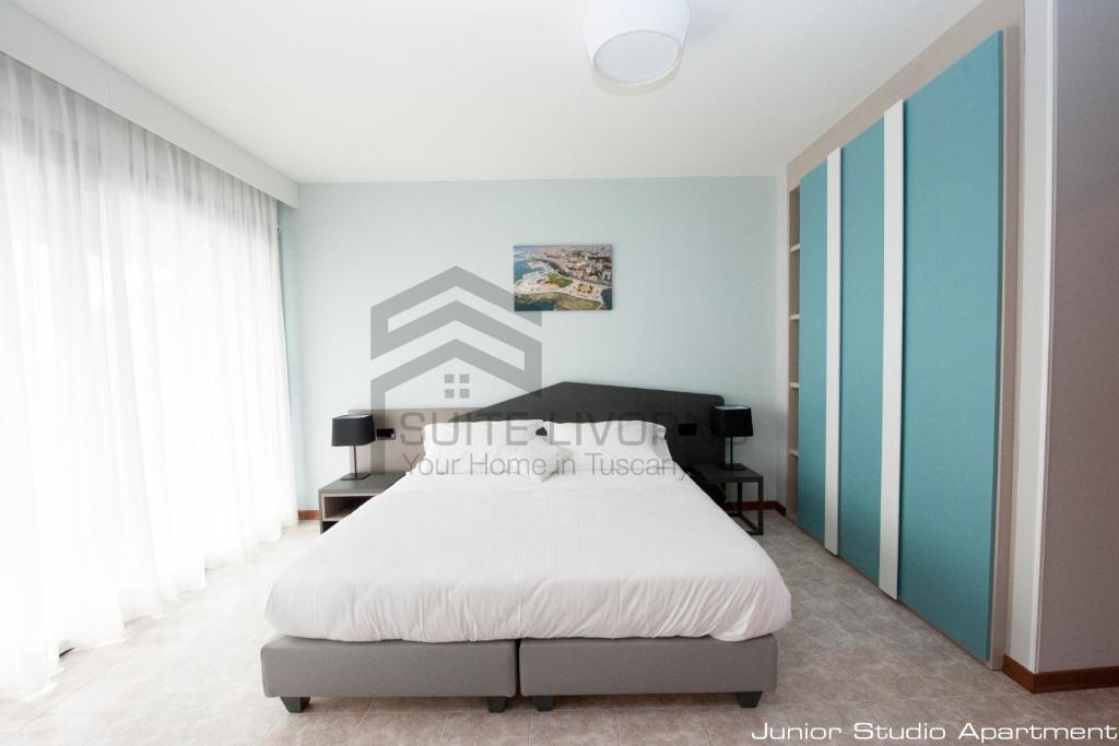 a bedroom with a white bed and blue walls at Suites Marilia Apartments - Suite Livorno Holiday Home Group in Livorno