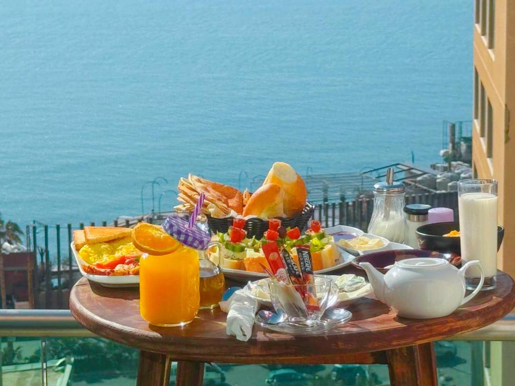 ベイルートにあるKing Suites Hotelの海を望むバルコニーにテーブルと朝食用の食材を用意しています。