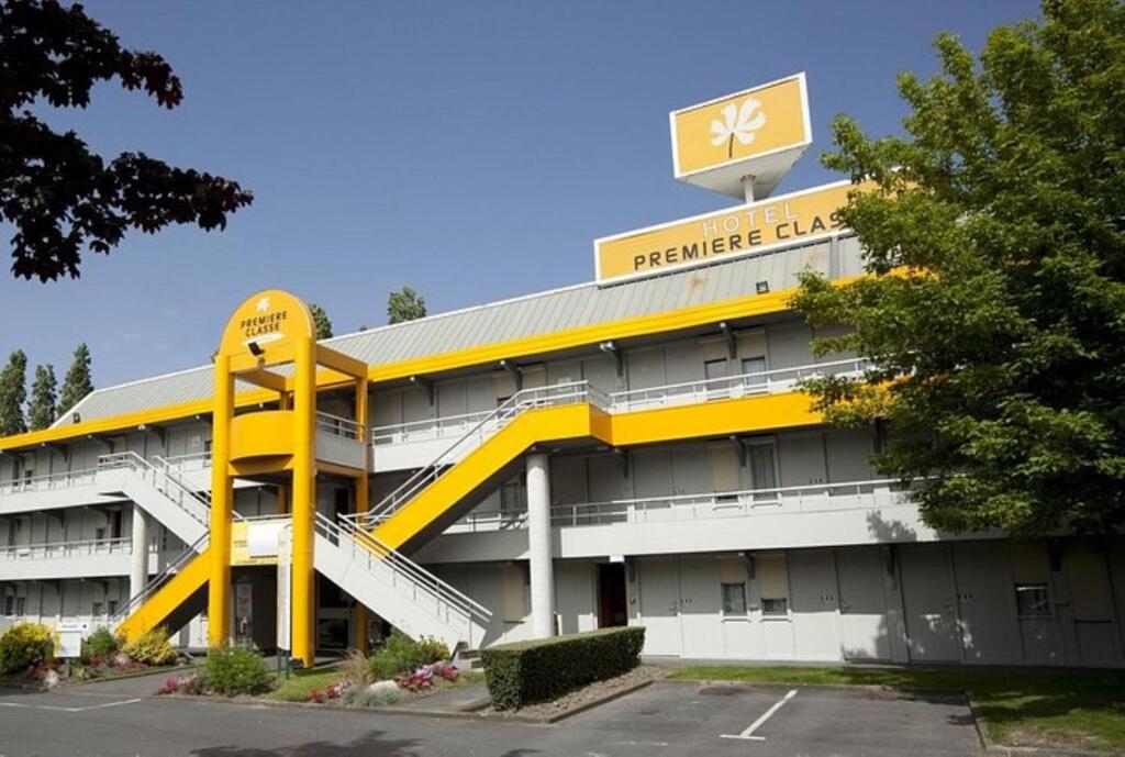 un edificio blanco y amarillo con aparcamiento en Premiere Classe Herblay, en Herblay