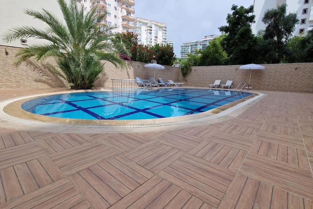 una piscina con azulejos azules en el suelo de madera en Happy Suites 9, en Alanya