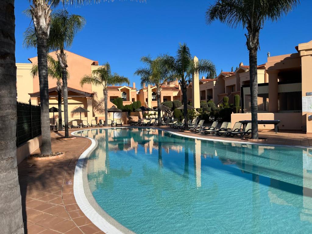 a large swimming pool with palm trees and buildings at Margarida Apartment in Luz