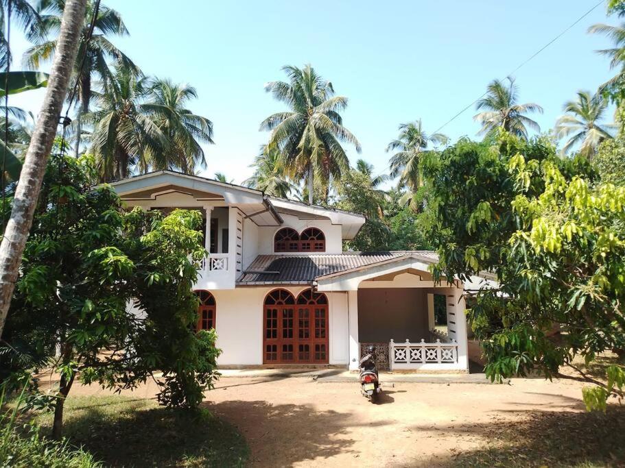 uma casa branca com palmeiras em frente em Holiday Home in Mirigama em Mirigama