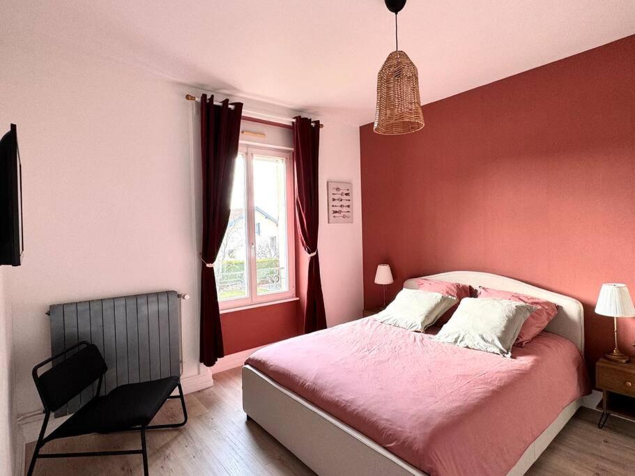 a bedroom with a bed with red walls and a window at L Étoilé Appartement tout confort à Epinal Gare Classé 3 étoiles in Épinal