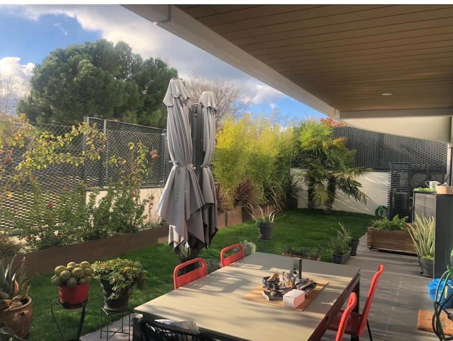 um pátio com um guarda-sol, uma mesa e cadeiras em Oasis Familiar, casa con jardín con ubicación Ideal em Alcobendas