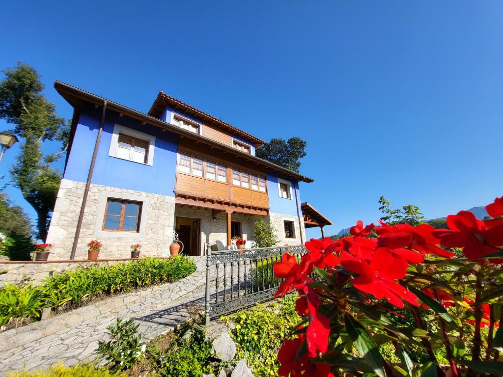 uma casa com flores vermelhas em frente em La Biesca Sebreñu em Ribadesella