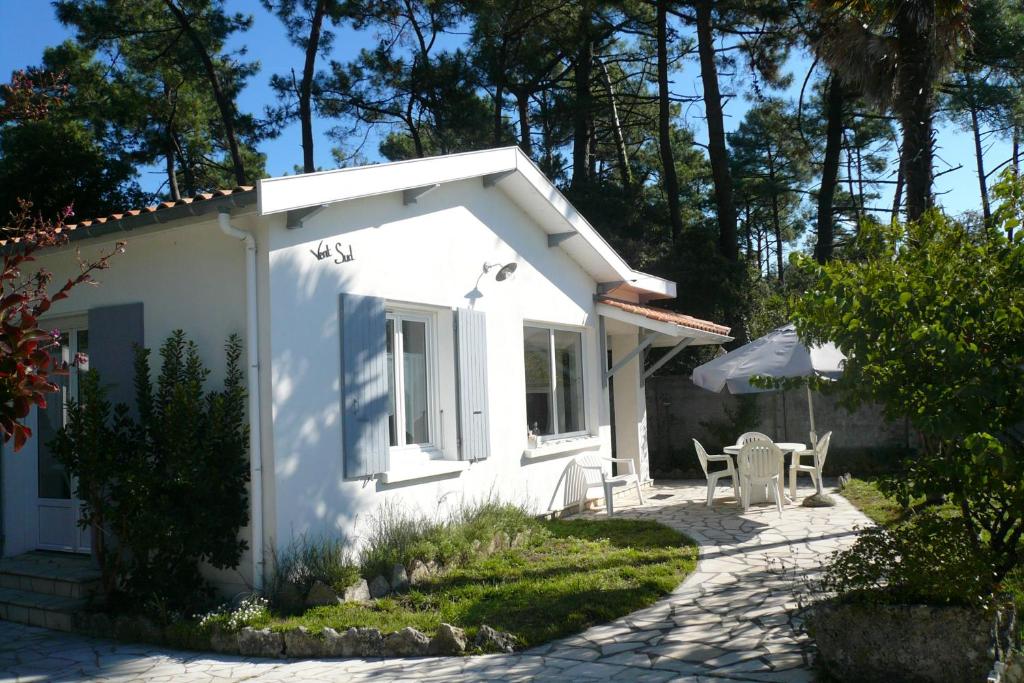 a white house with a patio and a table at Maison Vent du Sud in Saint-Trojan-les-Bains