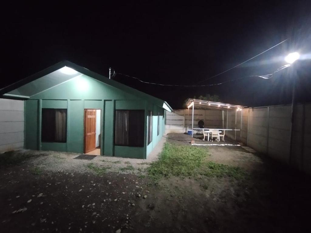 uma casa verde com uma mesa à frente à noite em Green Home em Talamanca