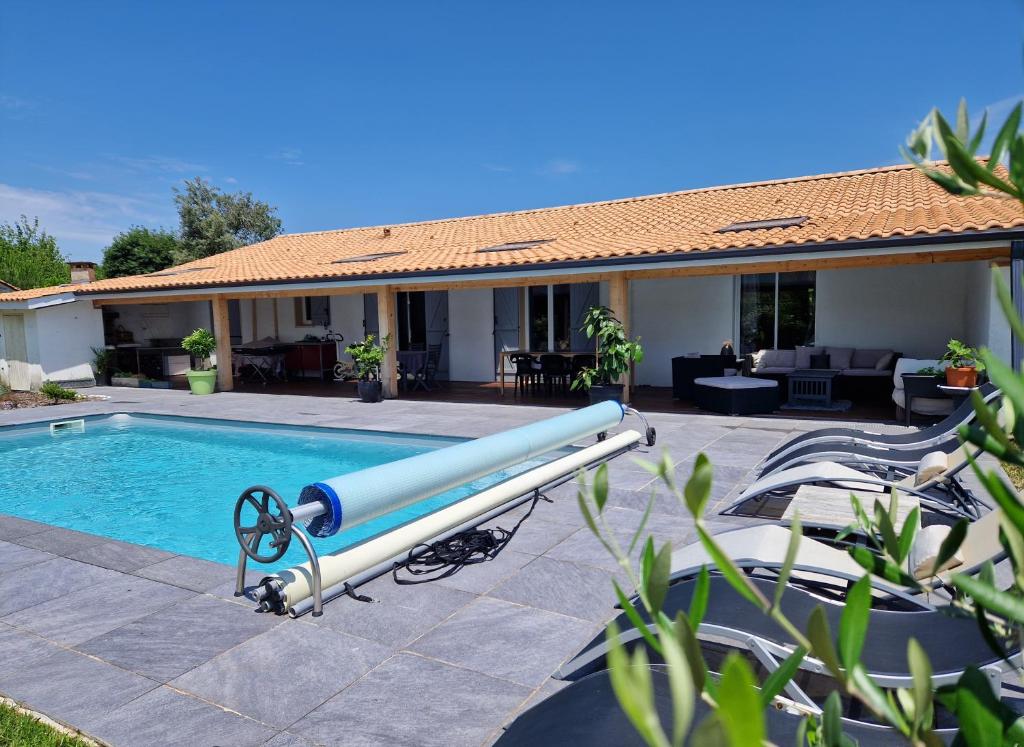 - une piscine avec un tube bleu à côté d'une maison dans l'établissement Chez Sophie, à Le Barp