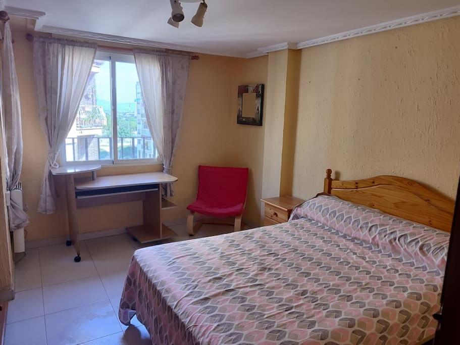 een slaapkamer met een bed, een bureau en een raam bij Flat in Quevedo Street near the Train Station in Castellón de la Plana
