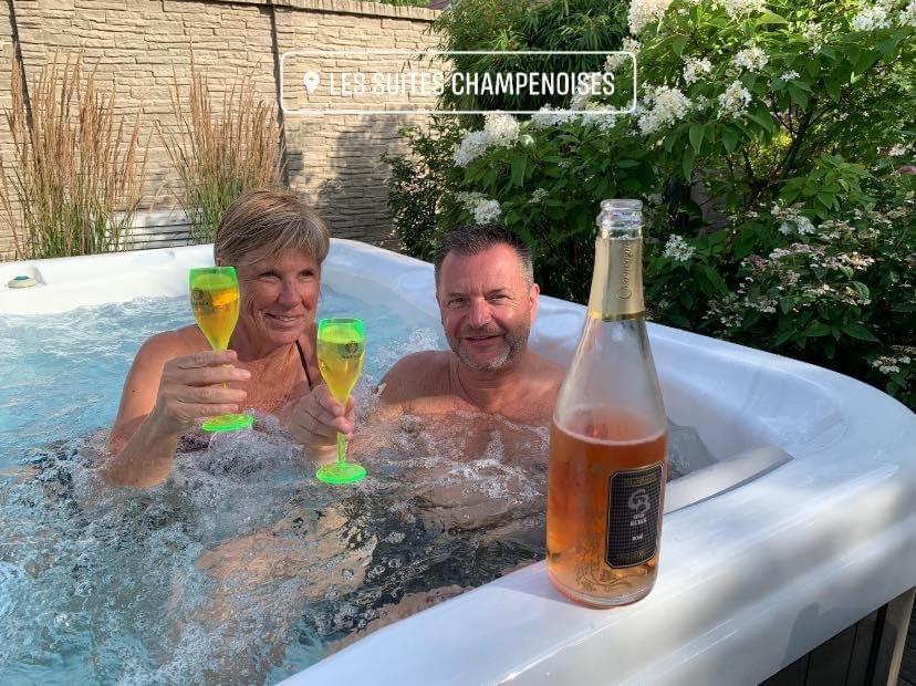 2 hommes dans un bain à remous avec des verres de champagne dans l'établissement Les Suites Champenoises, à Reims