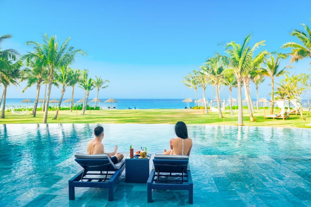 a couple sitting in the infinity pool at the resort at Hoi An Royal Beachfront Resort & Villas in Hà My Tây (2)