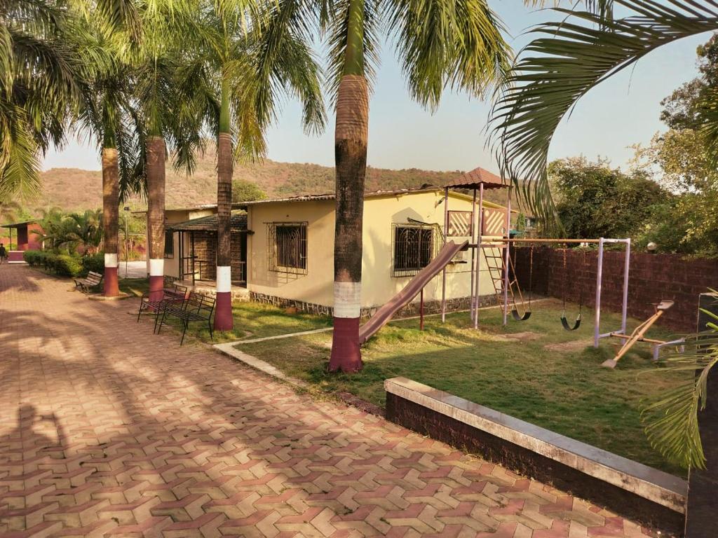 uma casa com um parque infantil com palmeiras em Nargis Farm Resort em Vihur