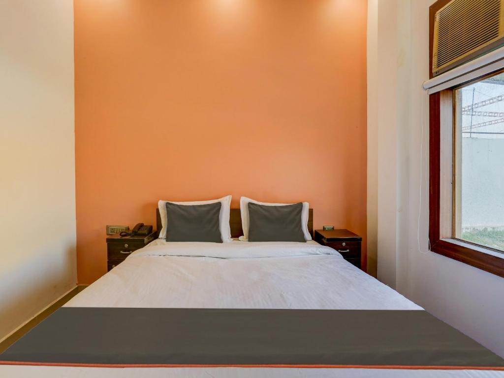 a bed in a room with an orange wall at North Hotel & Lawn in Lucknow