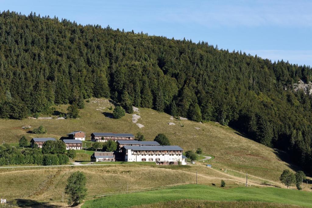 une grande maison sur une colline en face d'une montagne dans l'établissement Hôtel Club Le Risoux, à Bois-dʼAmont